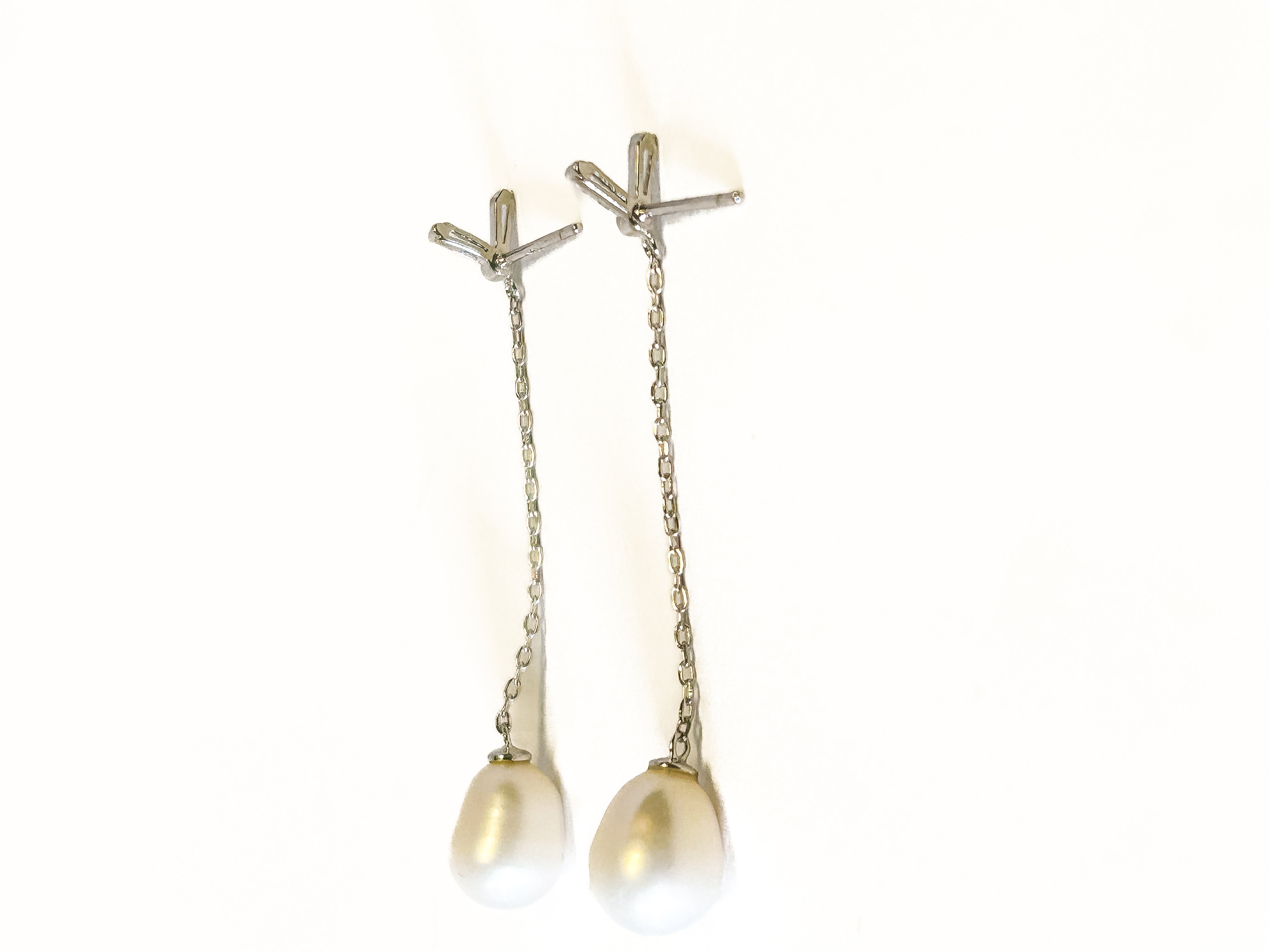 Pair of pearl earrings with chain on a white background